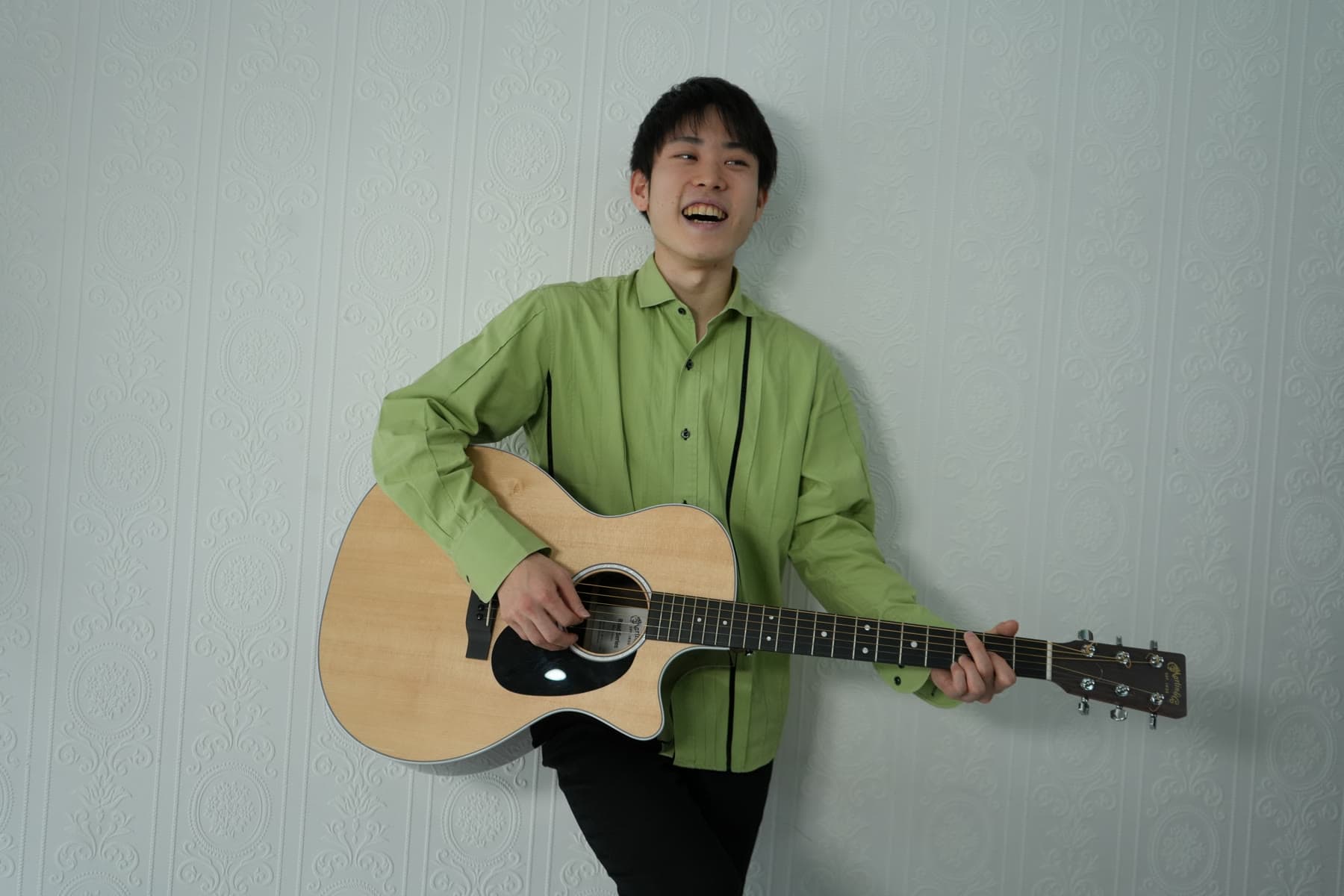 noshigeSound 創業者・田野奏多。アコースティックギターを手に笑っている写真